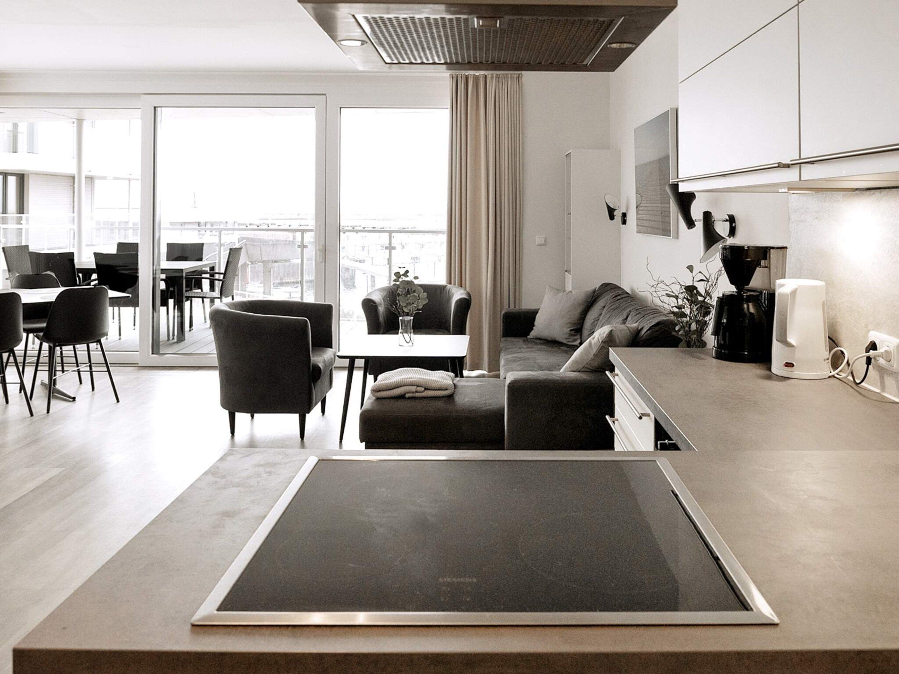 A modern living room with a sofa, a coffee table, and a dining area with chairs and a table.