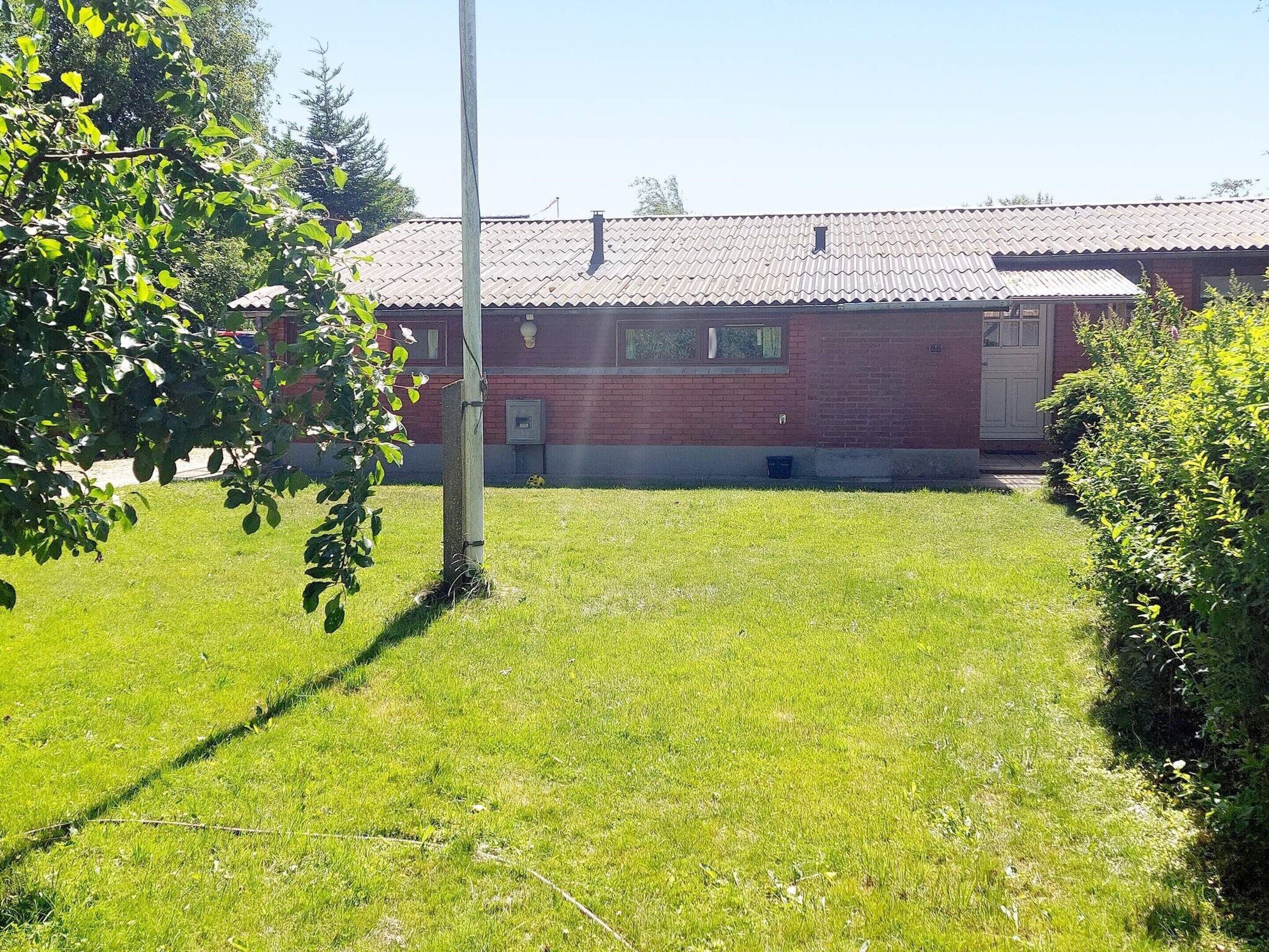 En græsplæne med en murstensbygning, et elmast og et lille vindue.