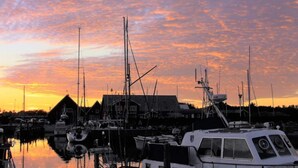 En lysthavn med både fortøjet i stille vand under solnedgang.
