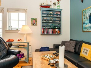 A living room with a bookshelf, a lamp, a coffee table with a candle, and a couch.