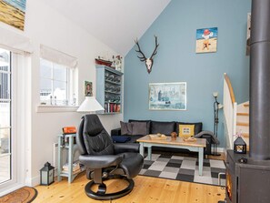 A cozy living room with a fireplace, a bookshelf, a dining table, and a comfortable seating area.