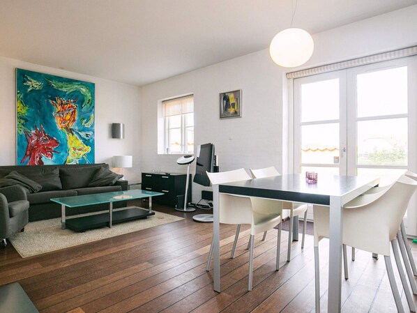 Ett modernt vardagsrum med en soffa, ett soffbord och en matplats med stolar och ett bord.