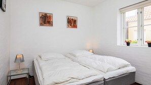 A bedroom with a bed, bedside lamps, and two paintings on the wall. - 4 Star Holiday Home in Skagen (Skagen)