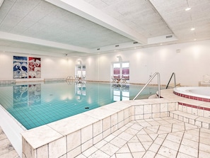 An indoor swimming pool with a tiled floor, a hot tub, and a seating area with chairs. - 4 Star Holiday Home in Skagen (Skagen)