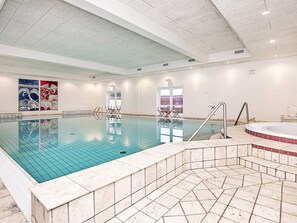 An indoor swimming pool with a tiled floor, a hot tub, and a seating area with chairs. - 4 Star Holiday Home in Skagen (Skagen)