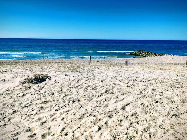 A beach with a clear view of the ocean, sandy terrain, and some rocks.