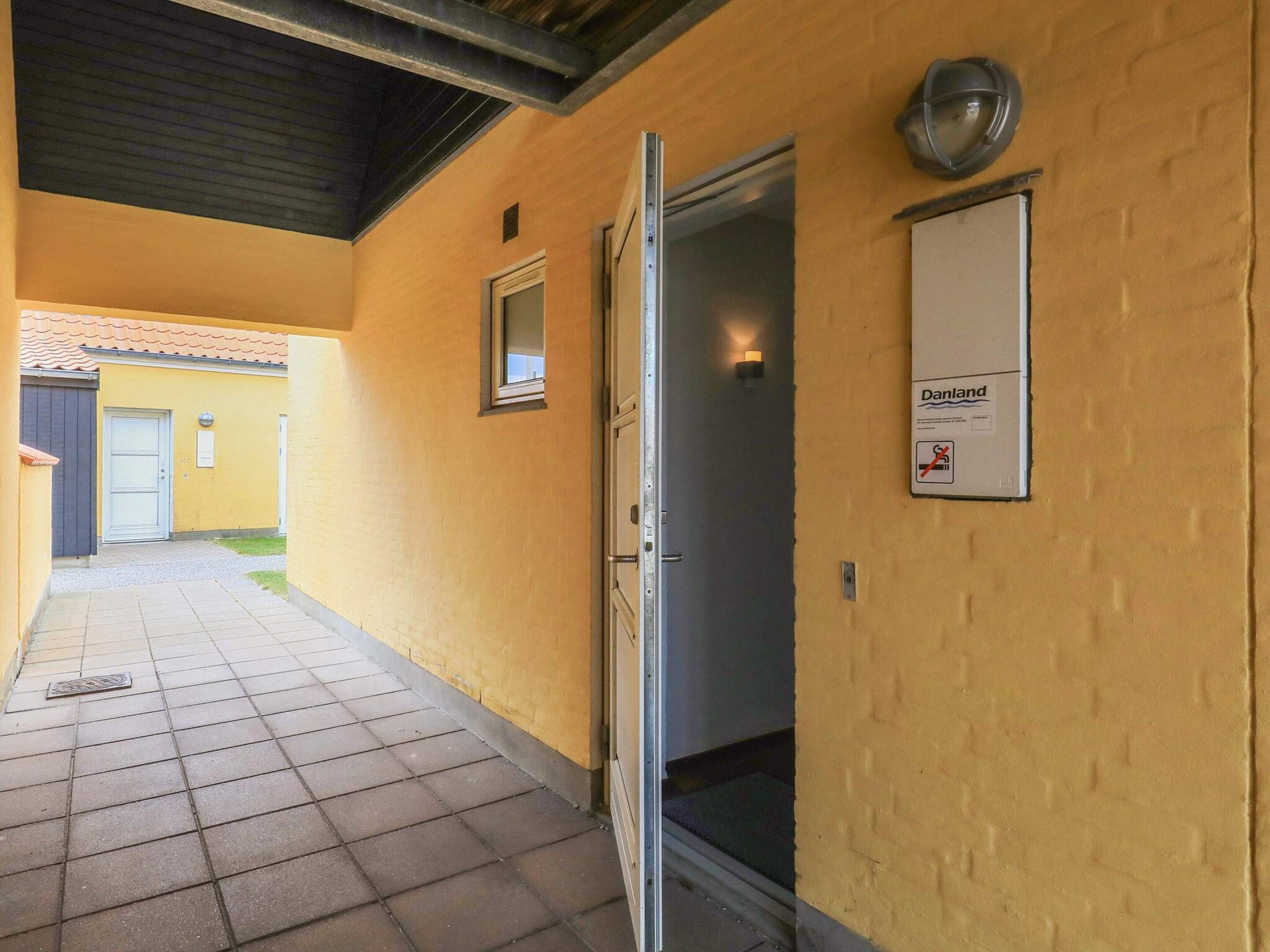 A corridor with a tiled floor, a door, and a wall-mounted sign.