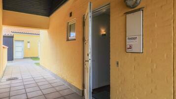 A corridor with a tiled floor, a door, and a wall-mounted sign.