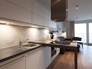 A modern kitchen with a built-in oven, a coffee machine, and a dining area with a table and chairs. - 5 Star Holiday Home in Wendtorf (Wendtorf)