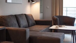 A modern living room with a sofa, armchair, and a small table with a cup and a book.
