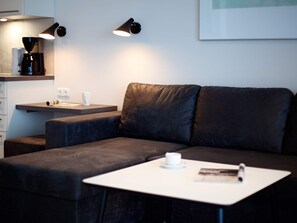 A modern living area with a sofa, a small table, and two wall-mounted lamps. - 5 Star Holiday Home in Wendtorf (Wendtorf)