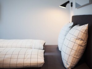 A bed with a dark headboard and two pillows with a grid pattern. - 5 Star Holiday Home in Wendtorf (Wendtorf)