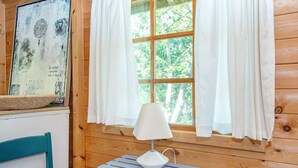 A wooden cabin room with a window, a table with a lamp, and a chair. - 7 Person Holiday Home in Ebeltoft (Ebeltoft)