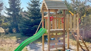 A wooden play structure with a green slide and climbing elements. - 9 Person Holiday Home in Vaeggerlose (Vaeggerlose)