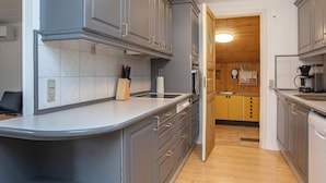 A modern kitchen with grey cabinets, a white countertop, and wooden flooring. - 9 Person Holiday Home in Vaeggerlose (Vaeggerlose)