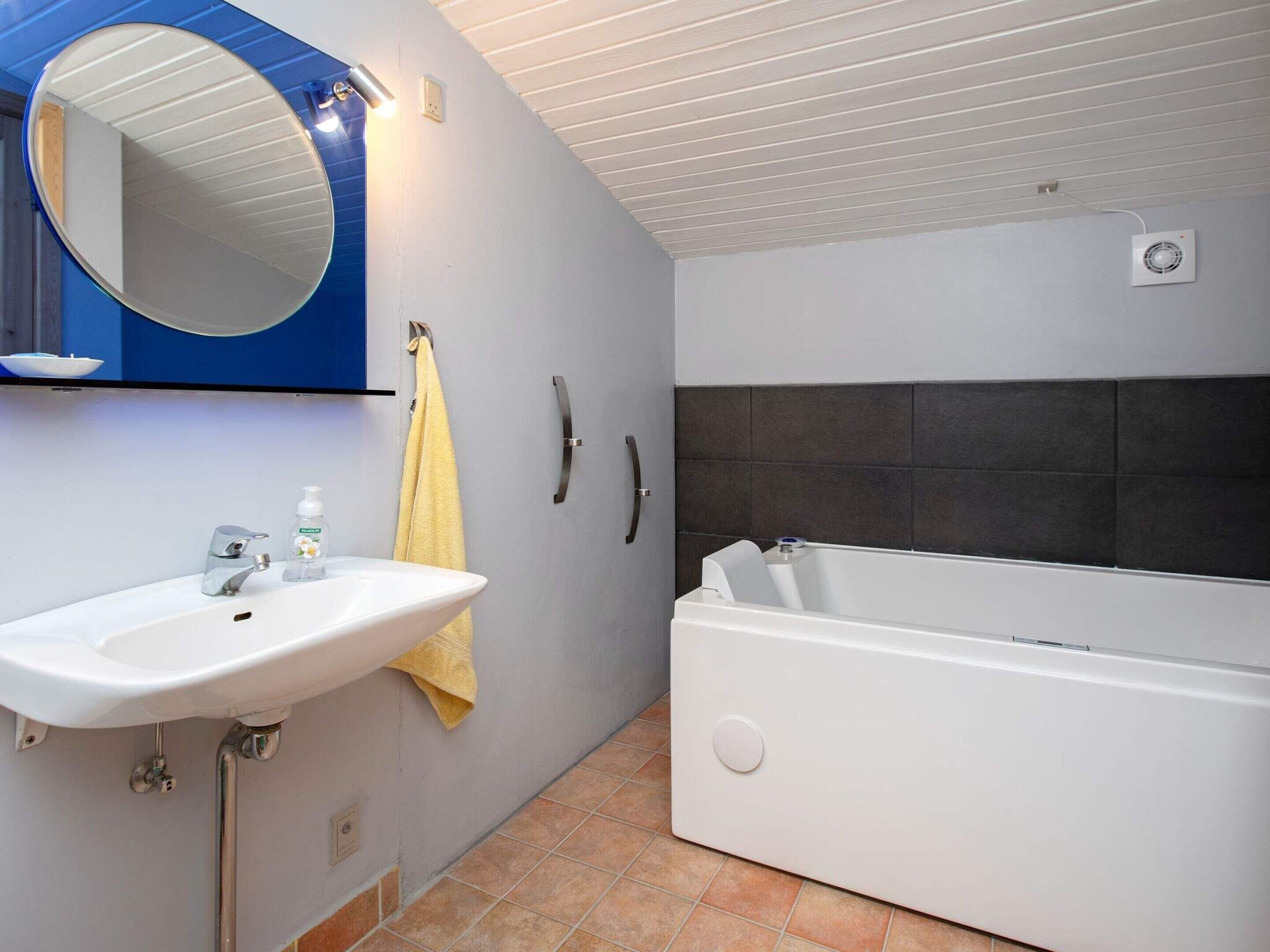 A bathroom with a white sink, mirror, and bathtub.