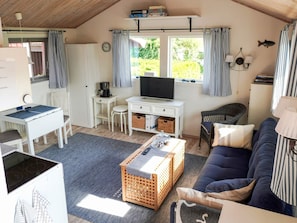Un salon confortable avec une télévision, un canapé et un coin repas comprenant une table et des chaises.