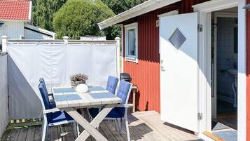 A wooden deck with a table and chairs, a barbecue grill, and a covered area with a white fence.