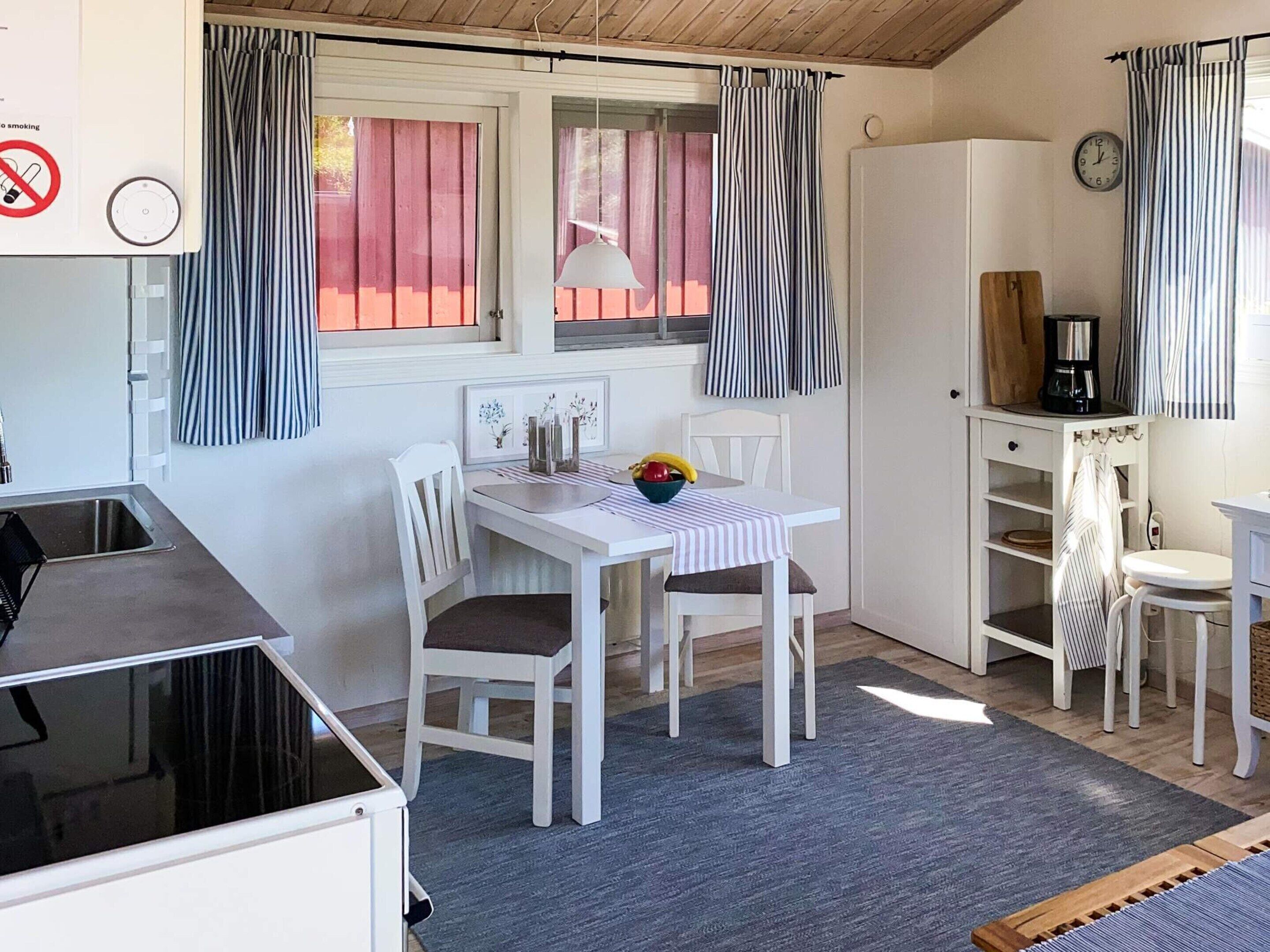 A compact kitchen with a dining area, a coffee machine, and a clock on the wall.