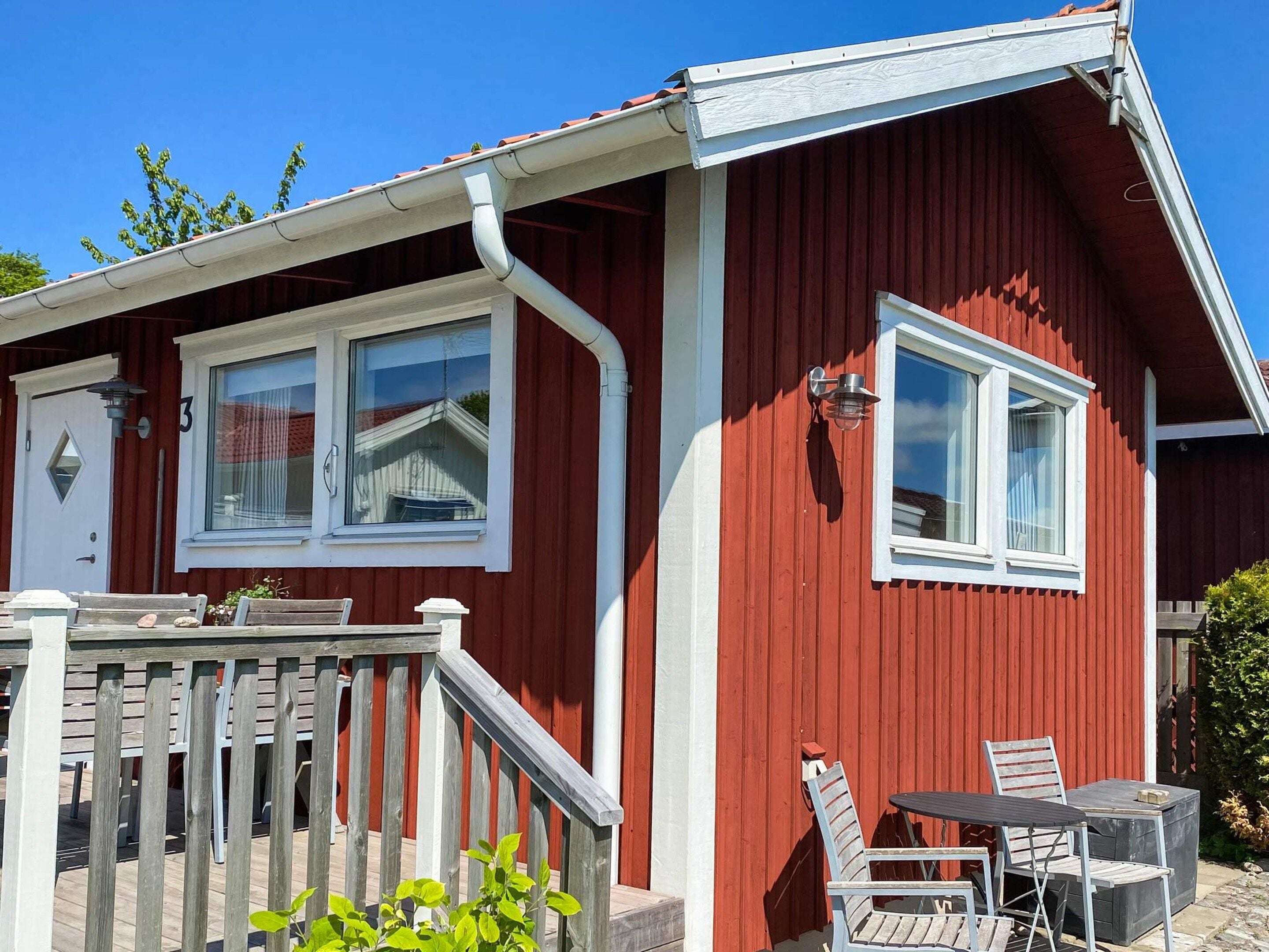 A red building with a white door, a window, and a small outdoor seating area with a table and chairs.