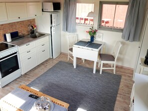 Une cuisine compacte équipée d’un four Bosch, d’un réfrigérateur, d’un four à micro-ondes et d’un coin repas avec une table et des chaises.