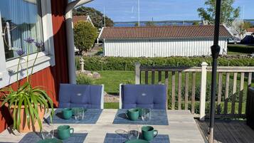 An outdoor patio with two blue cushioned chairs, a table set with green plates and glasses, and a potted plant.