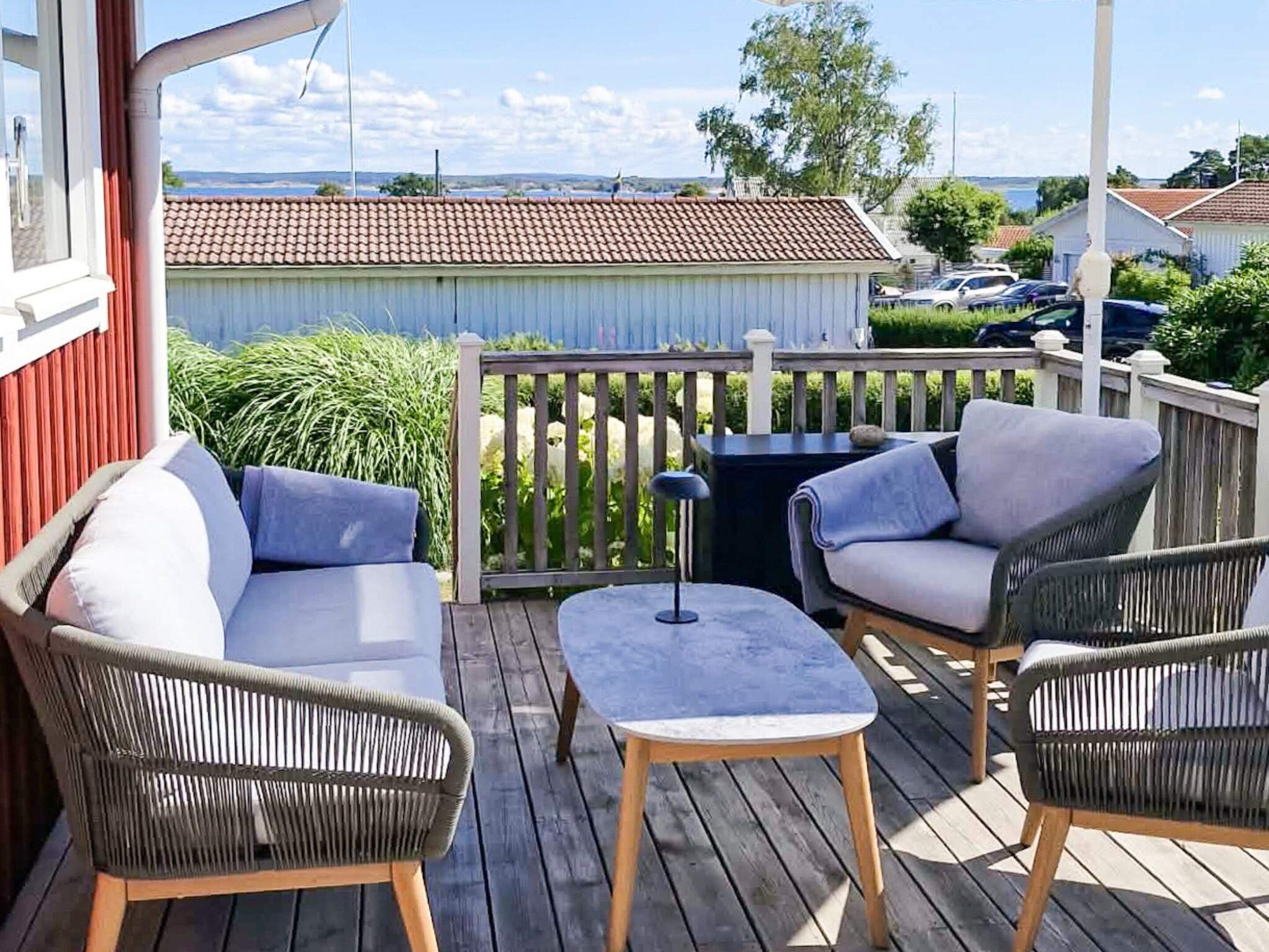 A wooden deck with outdoor furniture, including a sofa and chairs, and a view of the surrounding area.