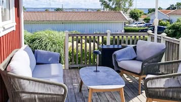 A wooden deck with outdoor furniture, including a sofa and chairs, and a view of the surrounding area.