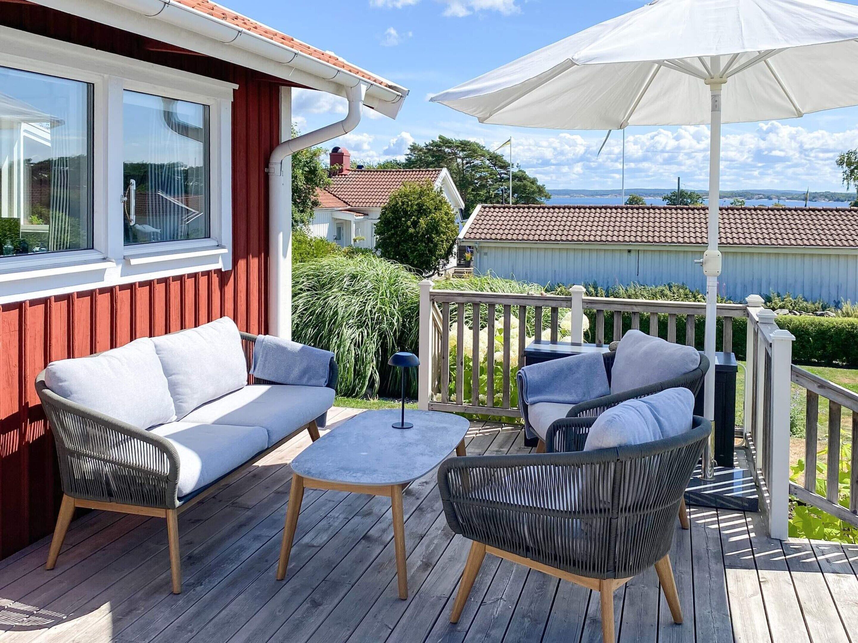 Um terraço com móveis de exterior, um guarda-sol branco e vista para uma área residencial.