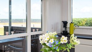 Ett kök med stora fönster, en kaffebryggare och en vas med blommor.