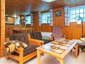 A cozy cabin interior with wooden walls, a dining area, and a seating area with a table and chairs.