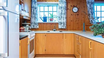 Una cocina con armarios de madera, un lavamanos, una estufa y un reloj en la pared.