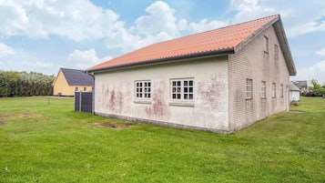A single-story building with a red roof, a small porch, and a grassy yard.