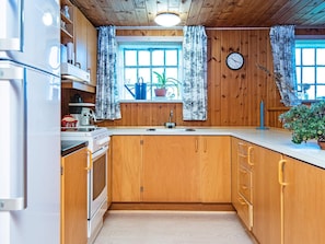 A kitchen with wooden cabinets, a sink, and a clock on the wall. - 6 Person Holiday Home in Ribe (Ribe)