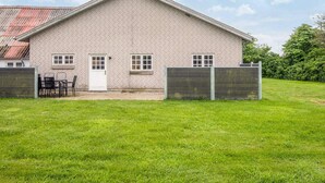 Un bâtiment d’un seul étage, construit en briques, avec un toit plat, une porte d’entrée et deux fenêtres.