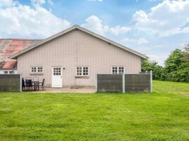 Um edifício térreo de tijolo com telhado plano, uma porta frontal e duas janelas.