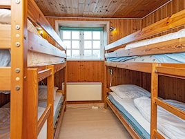 Quarto pequeno com beliches, janela e radiador.