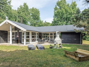 A house with a covered patio, outdoor seating, and a wood-burning stove. - 4 Star Holiday Home in Vaeggerlose (Vaeggerlose)