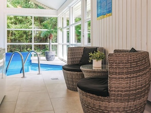 An indoor pool area with wicker furniture and a potted plant. - 4 Star Holiday Home in Vaeggerlose (Vaeggerlose)