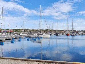 Ein Yachthafen mit mehreren Segelbooten an den Stegen, Holzstege und einem klaren Himmel.