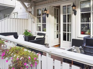 A balcony with wicker furniture and potted plants.