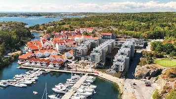 Una marina con barcos amarrados, un complejo de edificios con tejados rojos y un paisaje circundante.