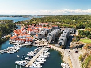 A marina with boats docked, a building complex with red roofs, and a hilly landscape in the background. - 4 Star Holiday Home in Stromstad (Stromstad)