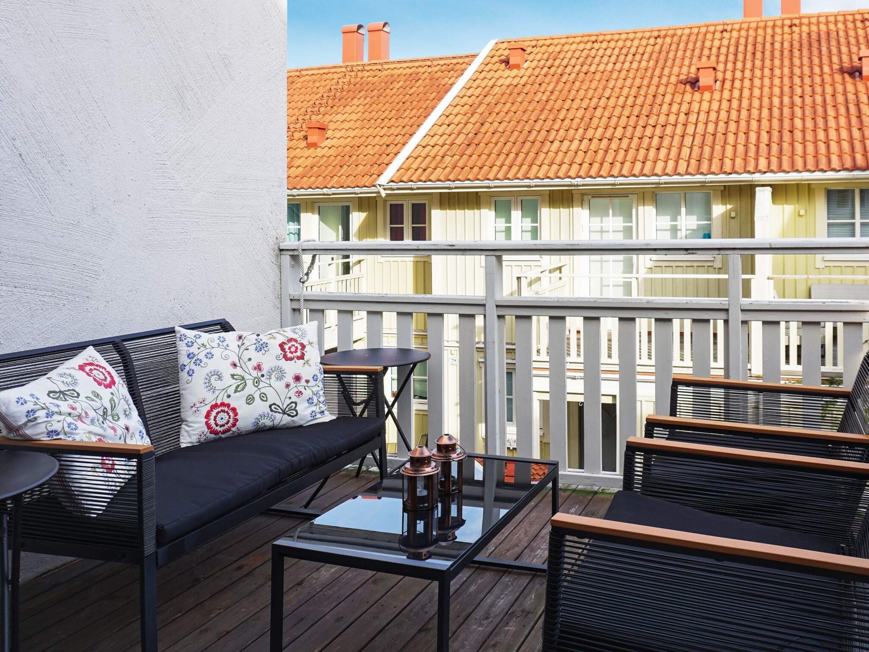 Un balcon avec un canapé, deux fauteuils, une petite table et une lanterne.