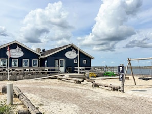 Un bâtiment situé sur la côte, avec une enseigne indiquant « Restaurant Pavillonen » et « Café Fjøden », et offrant une vue sur la mer.