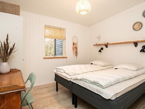 Une chambre à coucher comprenant un lit, un bureau, une chaise, une fenêtre avec des stores, un attrape-rêves et des lampes fixées au mur.