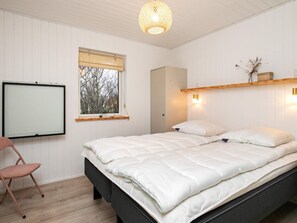 A bedroom with a bed, a chair, a window with blinds, a wall-mounted light, and a hanging light fixture. - 5 Star Holiday Home in Vinderup (Vinderup)