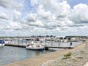 A marina with boats docked at wooden piers, a gravel walkway, and buildings in the background. - 5 Star Holiday Home in Vinderup (Vinderup)