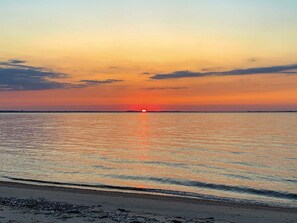 A beach at sunset with calm waters reflecting the sky.