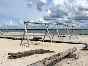 A wooden swing set on a sandy beach with a body of water in the background. - 5 Star Holiday Home in Vinderup (Vinderup)